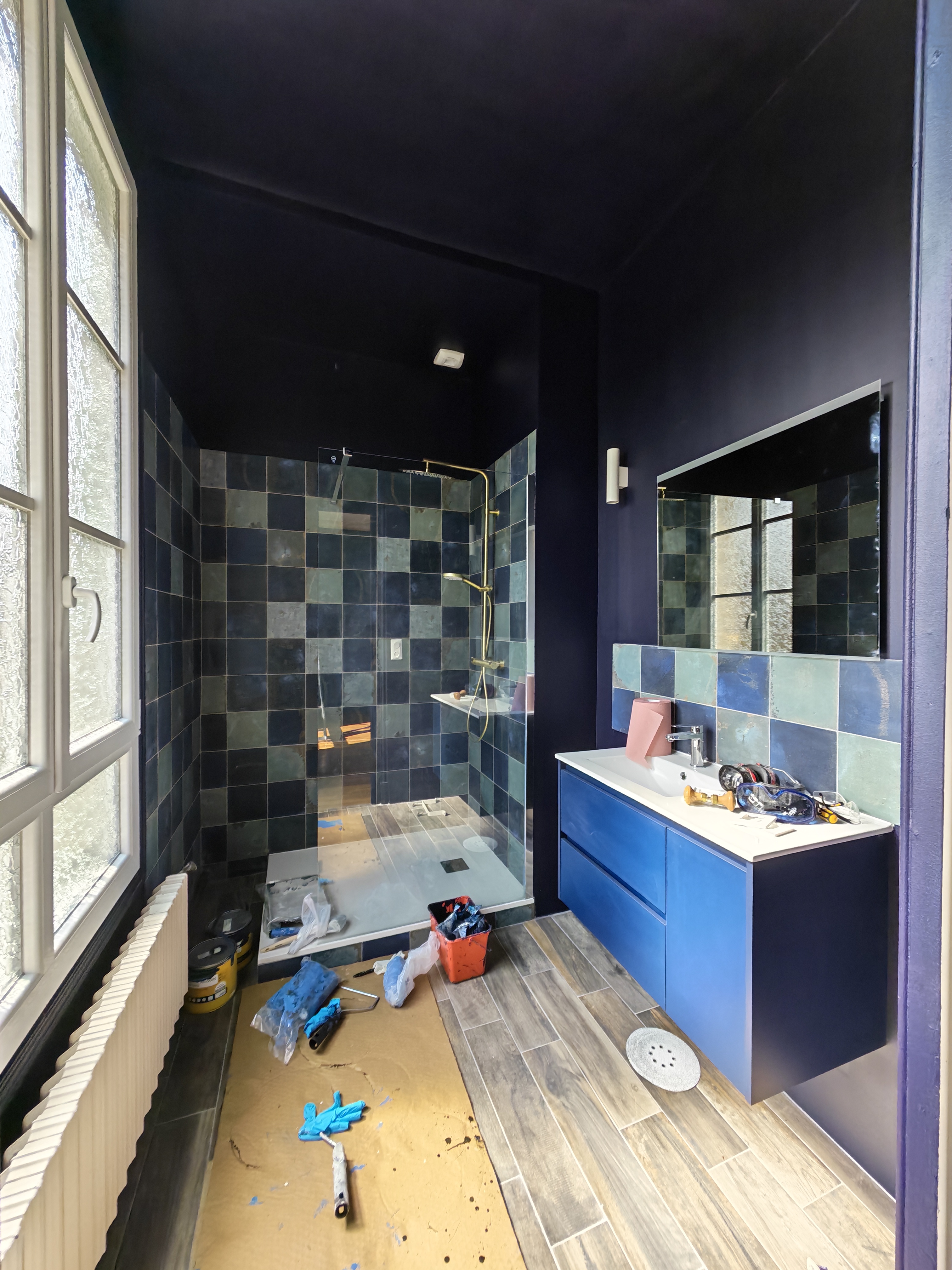 Salle de bain en rénovation, carreaux bleu-vert et robinetterie dorée